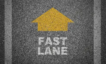 Yellow arrow pointing up above "Fast Lane" on asphalt.